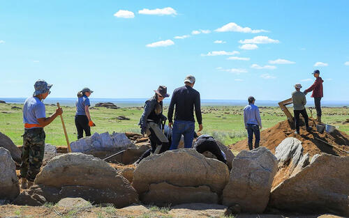 group of students digging and surrounded by large rocks
